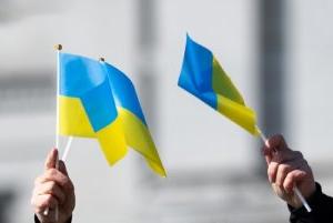 Close up of two h和s waiving Ukraine flags.