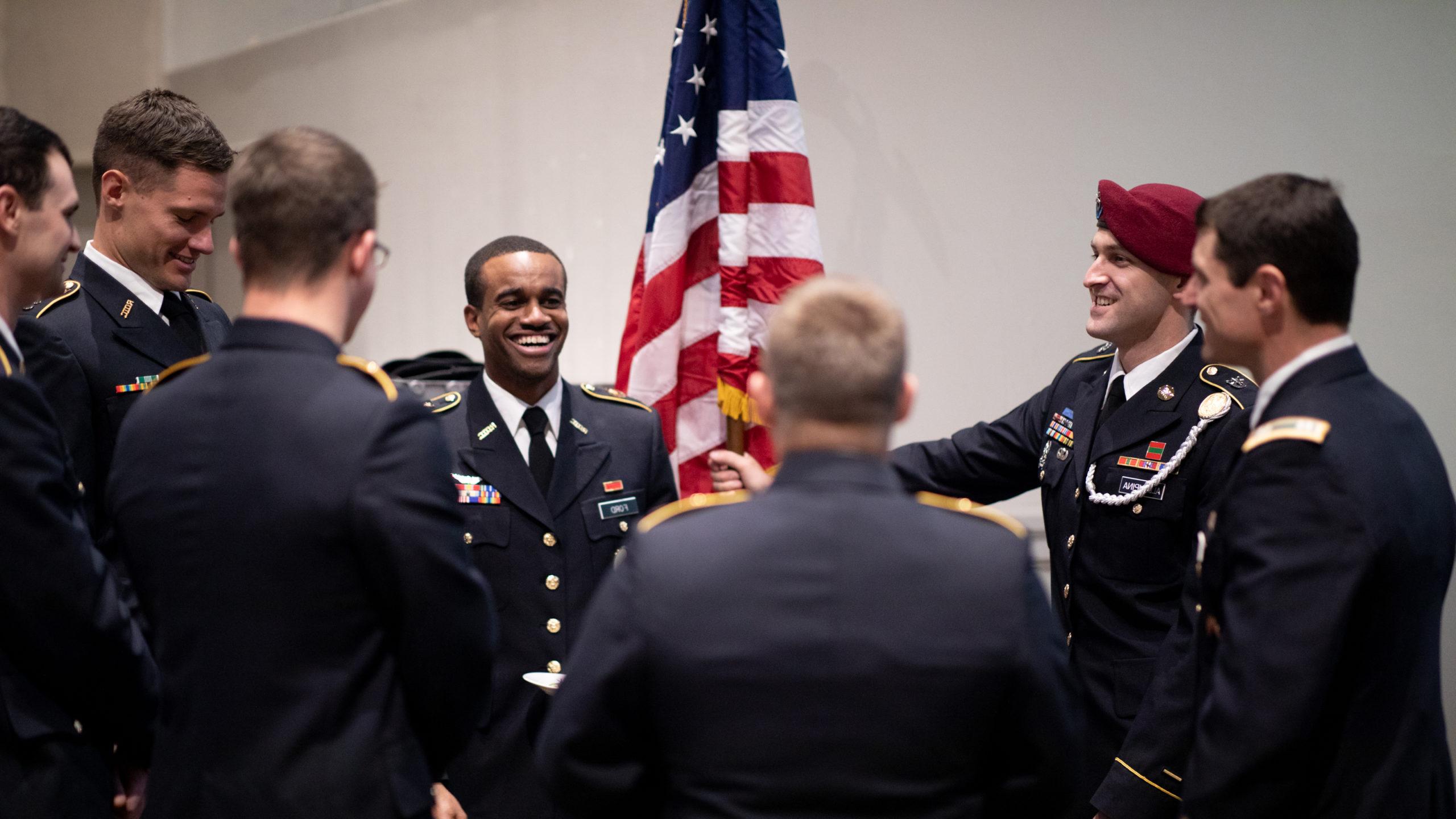 退伍军人毕业典礼，身着军装的毕业生在一面美国国旗前大笑