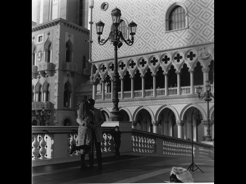Couple kissing in front of venetian type architecture.